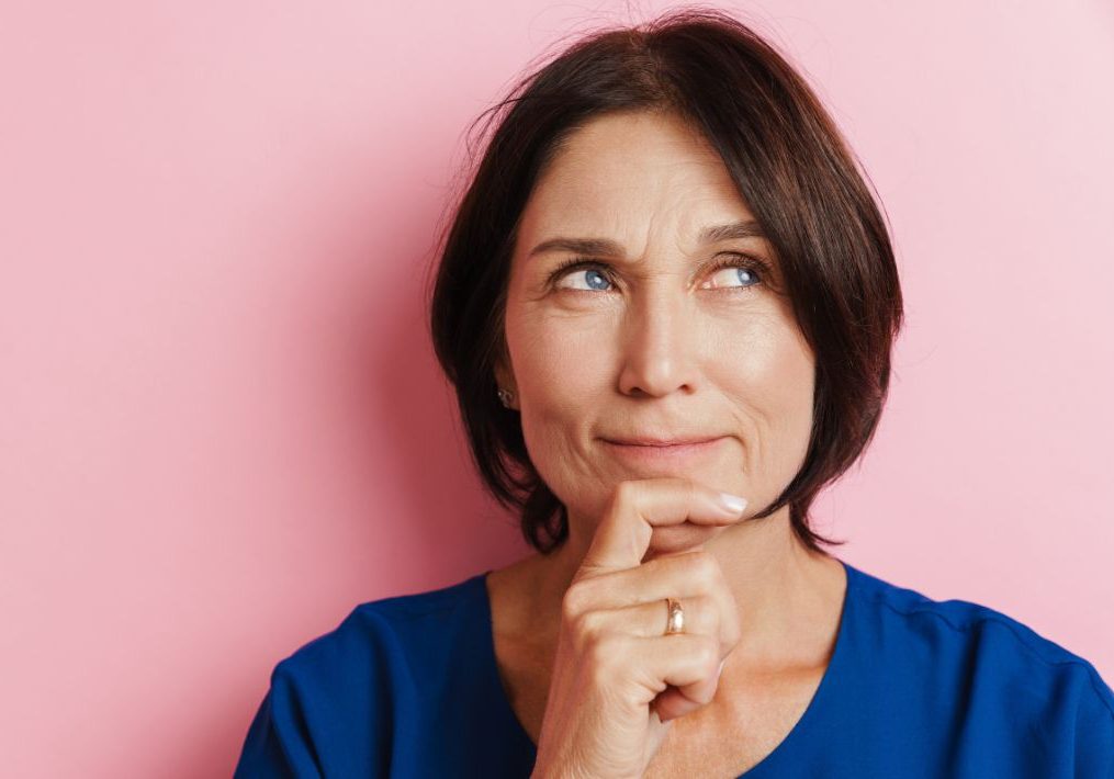 a middle age woman has her finger on a chin as she wonders curiously about functional medicine.